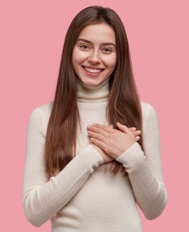 studio-shot-happy-cute-young-woman-folds-arms-chest-expresses-gratitude-swears-promises-something_273609-24271